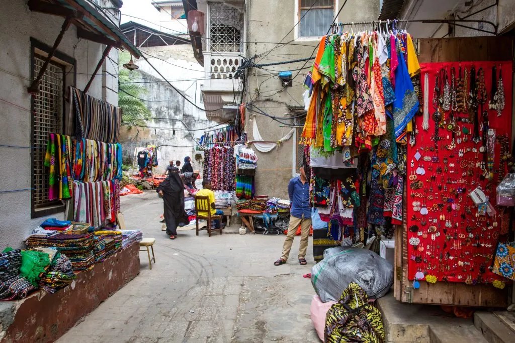 Tanzania, Zanzibar - 6/10/2018: una donna con il burqa cammina nel mercato all'aperto di Stone Town.