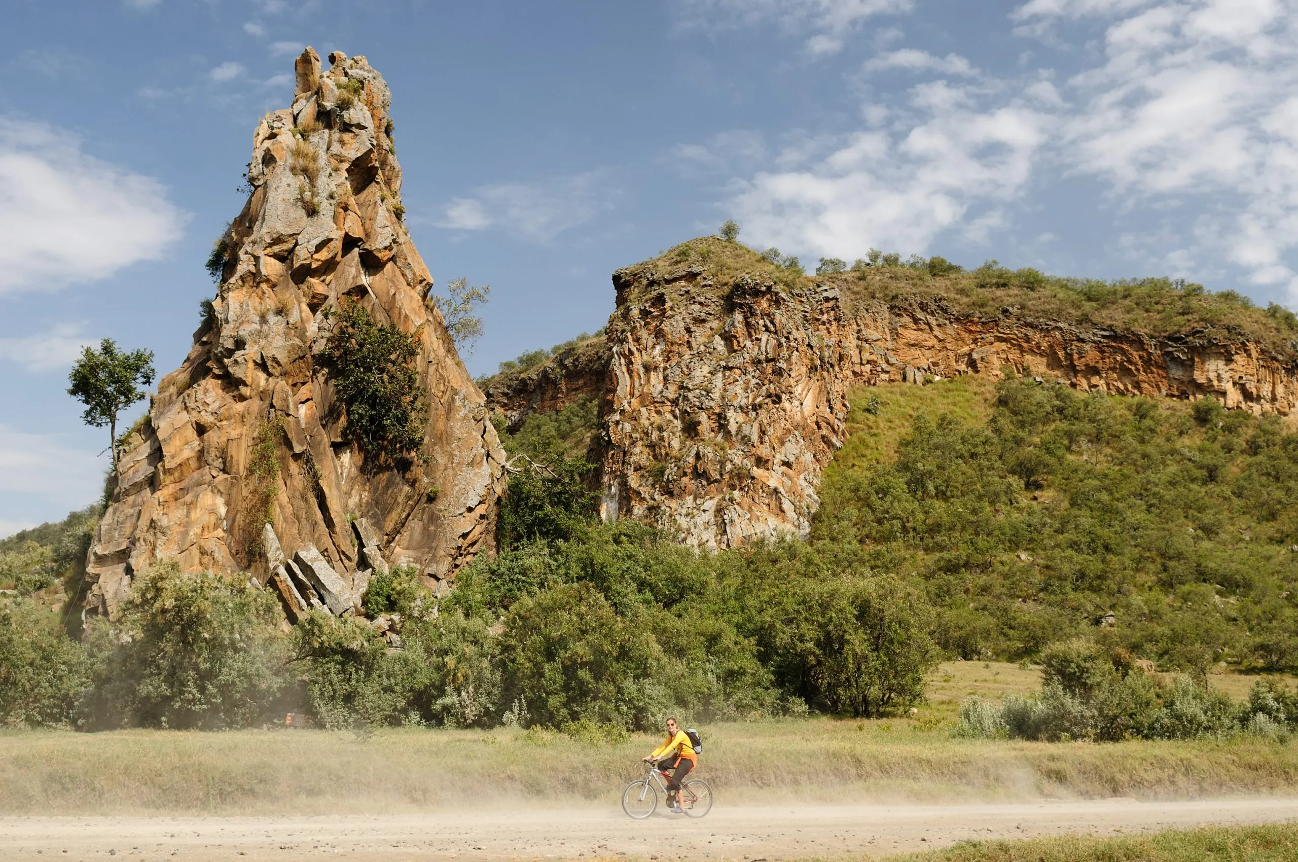The tourist is cycling at the foot Stark rock towers in the Hells Gate National Park in Kenya